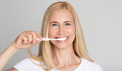 Oral hygiene concept. Middle-aged woman brushing teeth