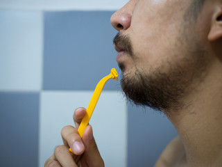 closeup man use yellow shaver shaving messy beard and mustache on his face in bathroom - 306733131