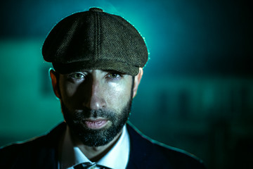 Man posing in the dark with a hat.