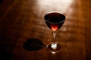 Dark alcohol cocktail stands on wooden table