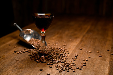 Alcohol cocktail, coffee beans and scoop on table