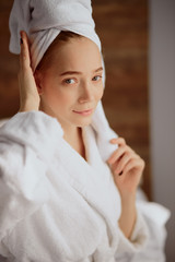 Impressive green eyes of charming lady looking at camera with pleasant feelings, expressing calmness, resting after shower in room of hotel, waiting for hairs to dry, wellness and spa concept