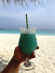 Frau hält einen Cocktail Swimming-Pool am Strand des Rasdhoo Atolls in ihrer Hand mit dem Meer im...