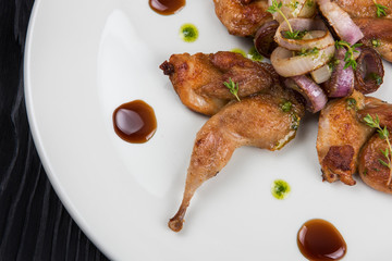 Roasted quails with vegetable on white plate