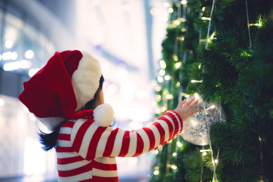 Portrait Of Cute Asian Little Girl Wear Santa Hat Happy Near Christmas Tree,Thailand Kid Join Christmas Festival