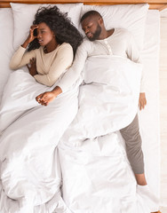 Afro woman annoyed by her boyfriend sprawled out all over bed
