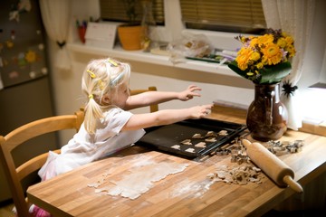 Little girl helping in kitchen preparing cooking and baking.