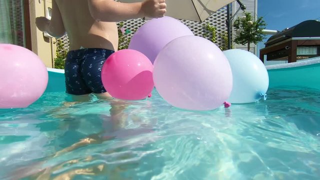 cute happy kids having fun, swimming in inflatable pool on the patio at home