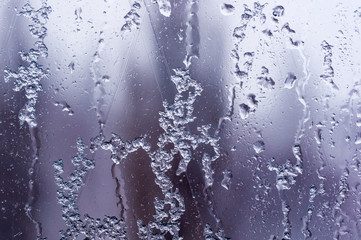 glass in the window covered with wet melting snow, close-up, macro photo
