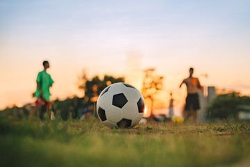 Silhouette action sport outdoors of diversity of kids having fun playing soccer football for exercise in community rural area under the twilight sunset sky.