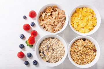 bowls of cereals, granola, corn flakes and fresh berries for breakfast, top view