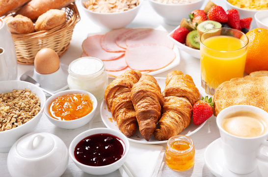 Breakfast with croissants, coffee, juice, meat, jam, cereals and fresh fruits