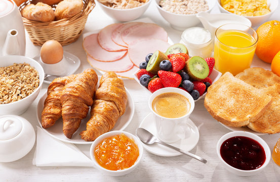 Breakfast with croissants, coffee, juice, meat, jam, cereals and fresh fruits