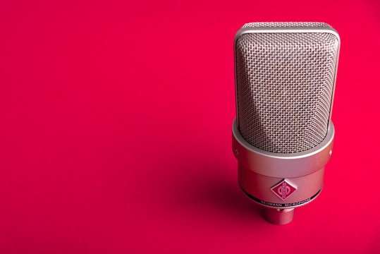 Uzhgorod, Ukraine - December 1, 2019: Large diaphragm condenser studio microphone Neumann tlm 103 on a red background.