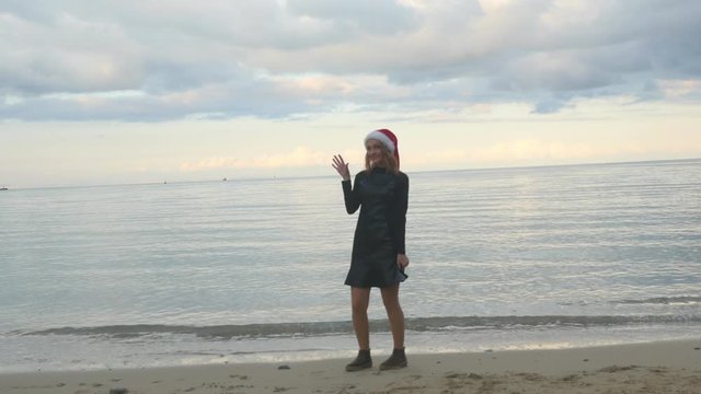 Funny woman in Santa hat funny walking by the sea