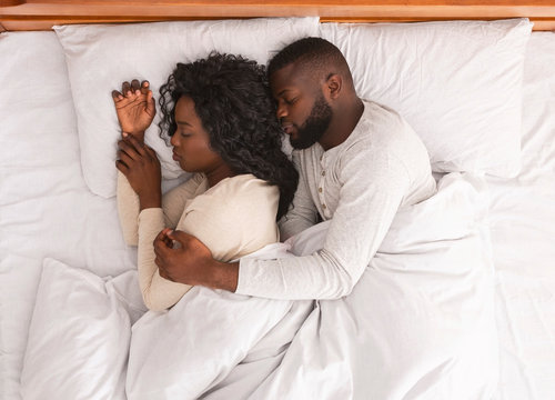 Married African Couple Sleeping In Bed And Cuddling, Top View