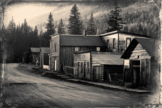 Vintage photo of old western buildings in the middle of mountains