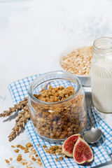healthy foods - homemade granola and milk on white table, vertical