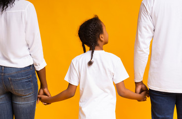 Rear view of african mother, father and daughter holding hands together