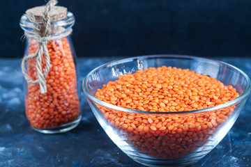 Red lentils in a plate and in a metal spoon on a background under concrete. Ideal food for vegetarians. Copy space. 