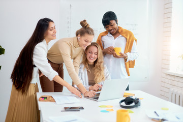 cheerful business people in office, positive process of coworking, young ladies of caucasian and african apperance together work