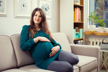 Pregnant woman on a couch in living room. pregnancy photo of a young woman. Vintage room and couch. 