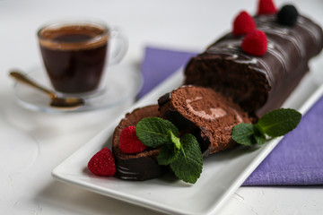 Sliced chocolate roll. Decorated with strawberries. Copy space. Christmas, New Year mood. Breakfast with a cup of coffee. 