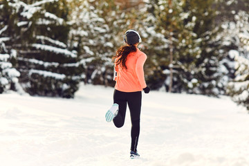 Girl jogging in the snow on the nature in winter.Back view
