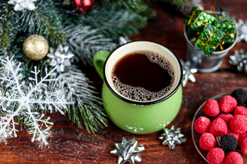 Hot coffee in a large ceramic, green cup. Christmas toys. New Year mood. On a dark background. Symbol of the coming year. Copy space. 