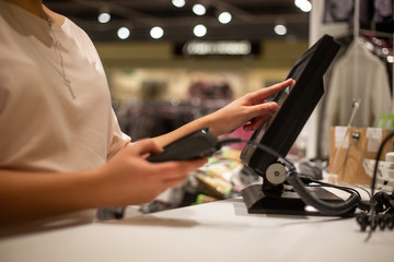 Young woman hands scaning / entering discount / sale on a receipt, touchscreen cash register, market / shop, finance concept, business