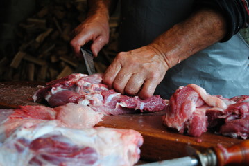 Butcher cuts fresh pork meat on a wooden cutting board