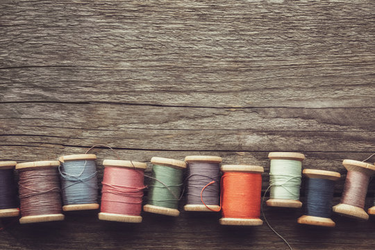 Row of vintage wooden spools of multicolored threads on wooden board. View from above. Copy space for text.