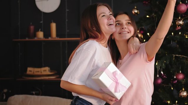 Christmas selfie. Winter holidays celebration. Two teen girls posing on smartphone camera with gift box.