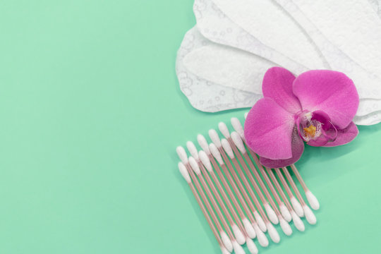 cotton buds, pads, gaskets on a mint background. Orchid flower. Eco-friendly