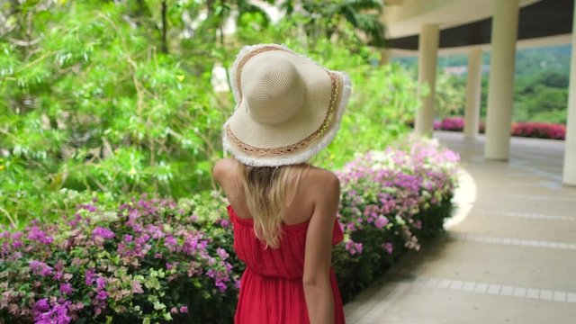 Pretty beautiful traveler woman girl in red dress walking with suitcase at luxury resort, Female tourist woman in tropical hotel. travel tourism ocean beach vacation happy holiday check-in slow-mo 4 K