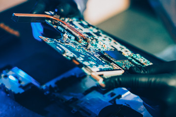 Computer manufacturing. Microelectronics engineering. Technician holding motherboard.