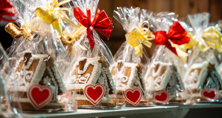 Christmas handmade gingerbread cookies on wooden shelf, set of small house shaped cakes, packed with red and gold bow