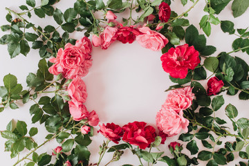 Round wreath frame border made of pink and red rose flowers and leaves. Flat lay, top view copy space mockup background. Valentine's day composition.