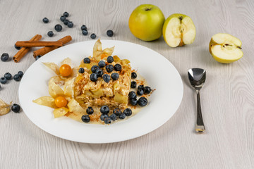 Baked apple slices with cottage cheese on a white plate on the table