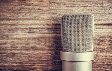 Large diaphragm condenser studio microphone. On a wooden background.