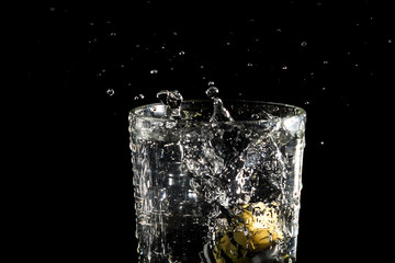 Toy mignon that fell into a glass of water on a black background under studio lighting