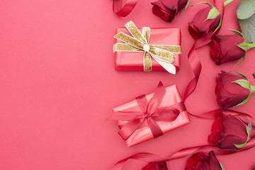 Valentine's Day, red roses and gift box with ribbon, over red background flat lay, birthday abstract background with copy space.