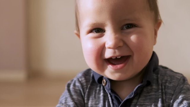 Cute baby smiling and looking at camera close up on the face.