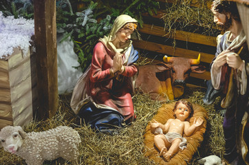 Christmas Nativity scene with The Holy Child, The Blessed Virgin Mary, Saint Joseph, ox and donkey in evening. Selective focus, noise effect © Максим Галінский