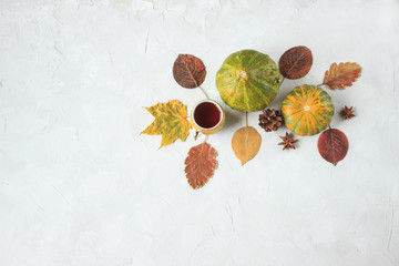 two decorative pumpkins and a Cup of tea on a gray concrete background, autumn minimalism, top view, space for text
