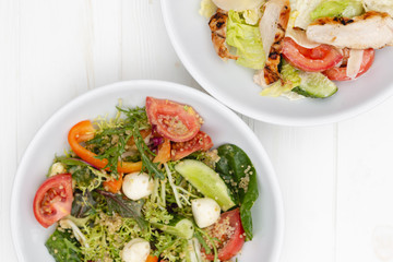 white deep plates with fresh salad ingredients mixed with sauce placed on an attractive background. A place for a menu, banner or advertisement