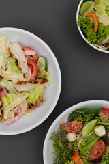 white deep plates with fresh salad ingredients mixed with sauce placed on an attractive background. A place for a menu, banner or advertisement