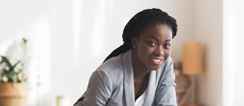 Portrait of black female employee leaned over something at workplace