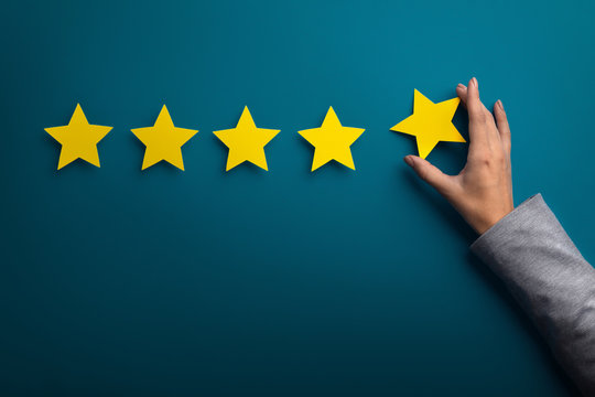 Woman hand giving five star rating on green