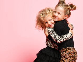 Two happy kids girls best friends sisters in leopard print clothes pants and sweater are hugging laughing having fun